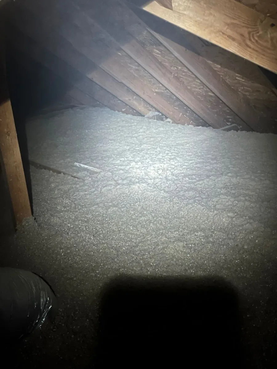 Loose-fill cellulose insulation meeting exposed wood framing beneath attic rafters