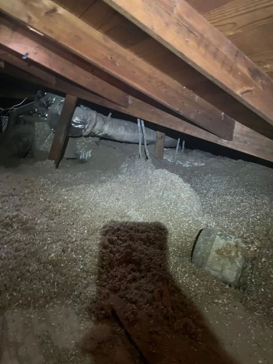 Loose-fill cellulose insulation spread across an attic floor around framing and ductwork