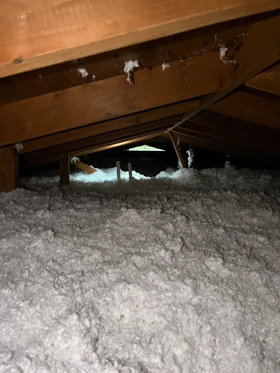 Fiberglass insulation installed across a wood-framed attic floor