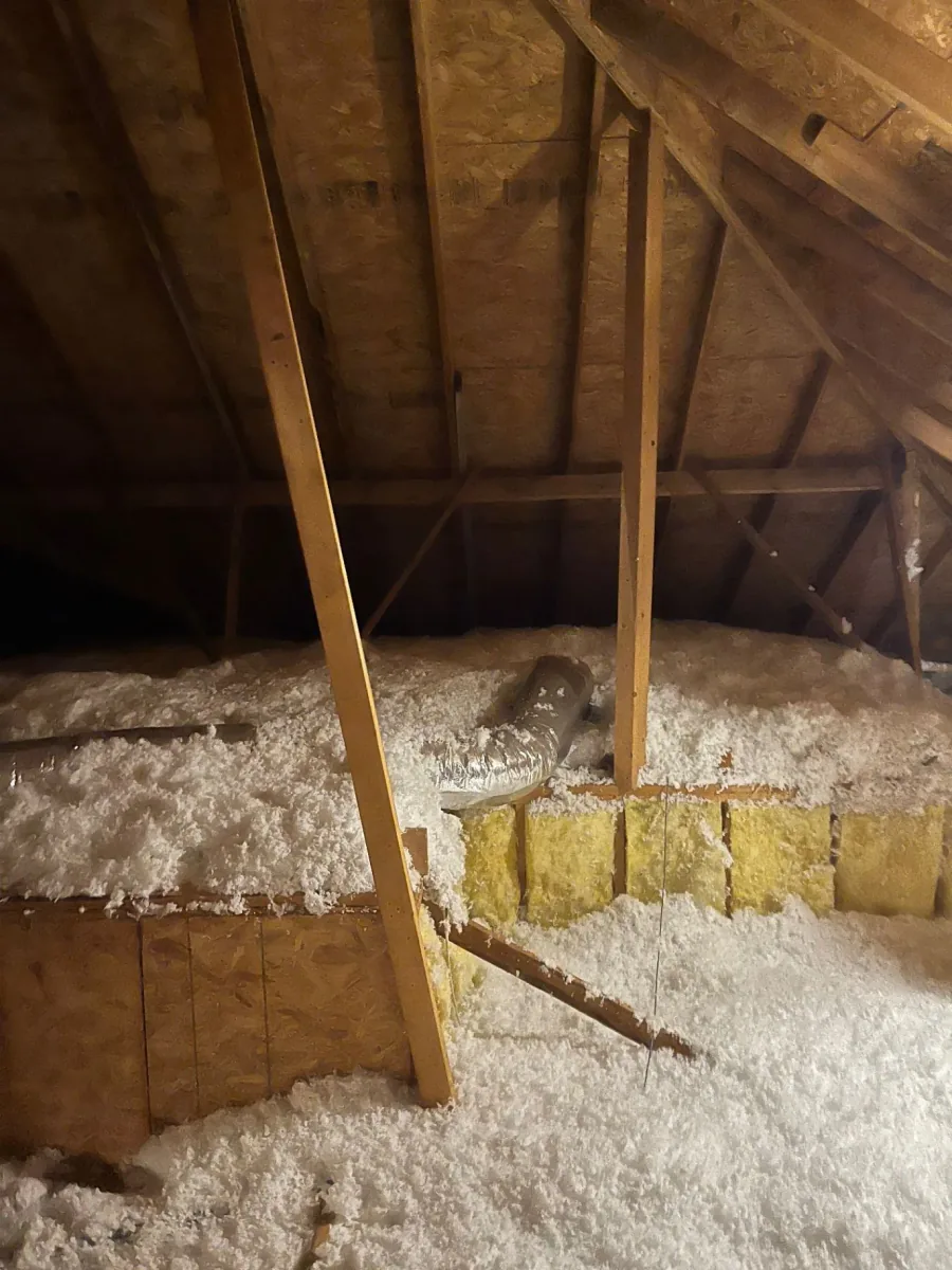 Fiberglass insulation filling the spaces between attic framing members