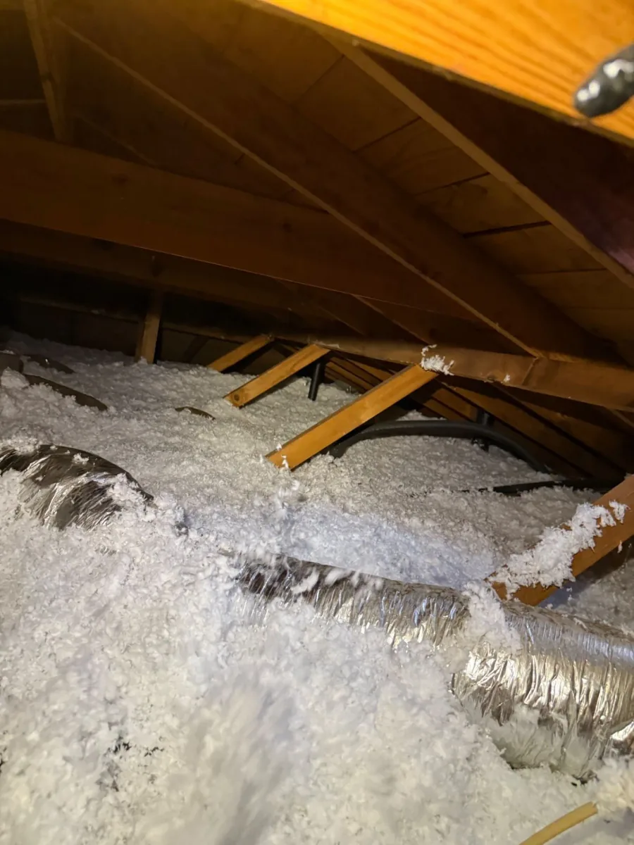 Fresh white fiberglass insulation covering the floor of a wood-framed attic