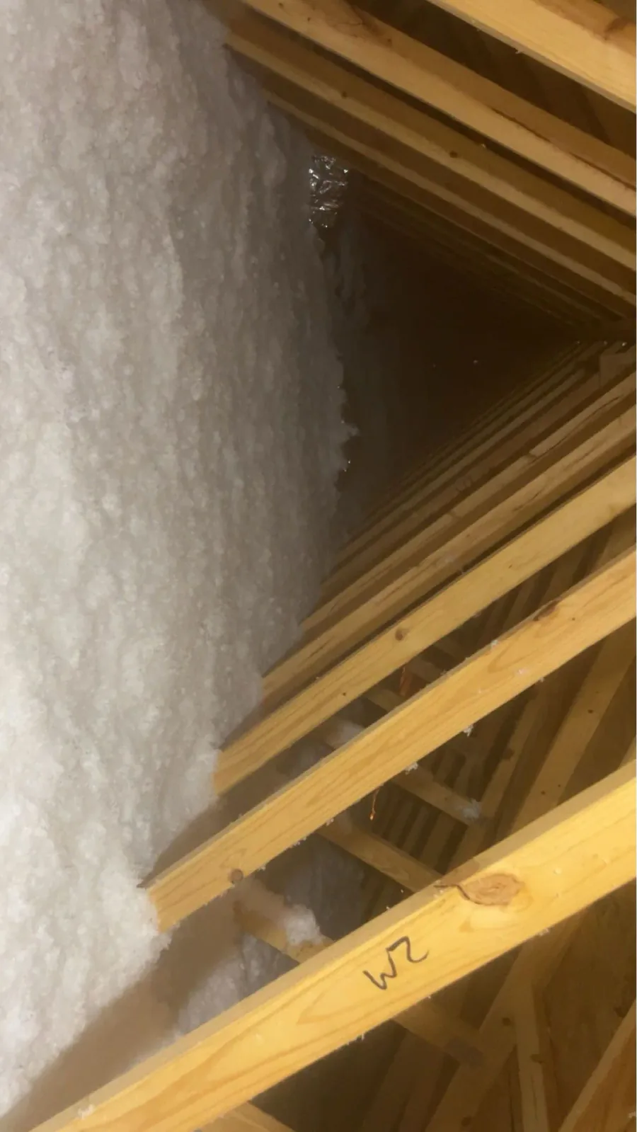 Fiberglass insulation installed around the framing in a pitched attic space